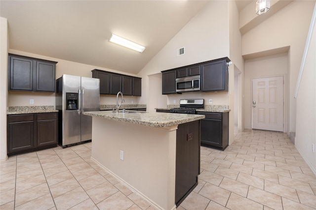 kitchen with visible vents, appliances with stainless steel finishes, a sink, an island with sink, and light stone countertops