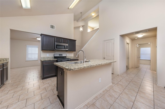 kitchen with light tile patterned floors, visible vents, appliances with stainless steel finishes, a sink, and light stone countertops