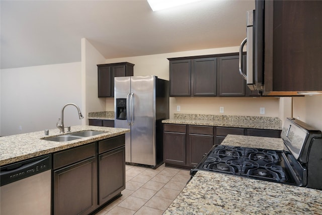 kitchen featuring dark brown cabinetry, light tile patterned floors, appliances with stainless steel finishes, vaulted ceiling, and a sink