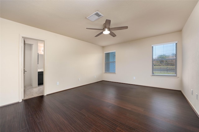 spare room featuring dark wood-style floors, visible vents, and ceiling fan