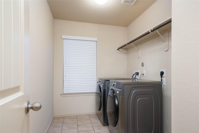 clothes washing area with laundry area, light tile patterned floors, visible vents, and washer and dryer