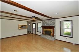 unfurnished living room featuring a fireplace, wood finished floors, and beamed ceiling