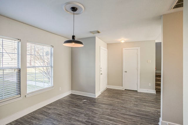 empty room featuring stairs, visible vents, and dark wood-style flooring