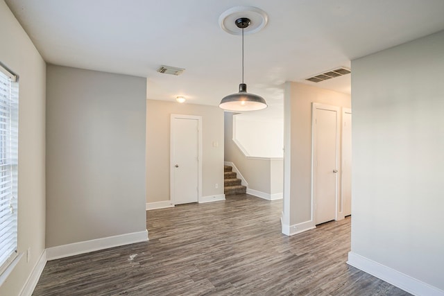 unfurnished room featuring baseboards, visible vents, stairway, and dark wood-style flooring