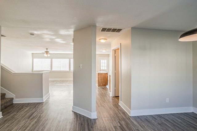 hallway with baseboards, visible vents, and dark wood-type flooring