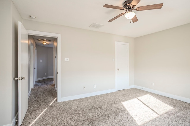 unfurnished bedroom featuring carpet flooring, a ceiling fan, visible vents, baseboards, and attic access