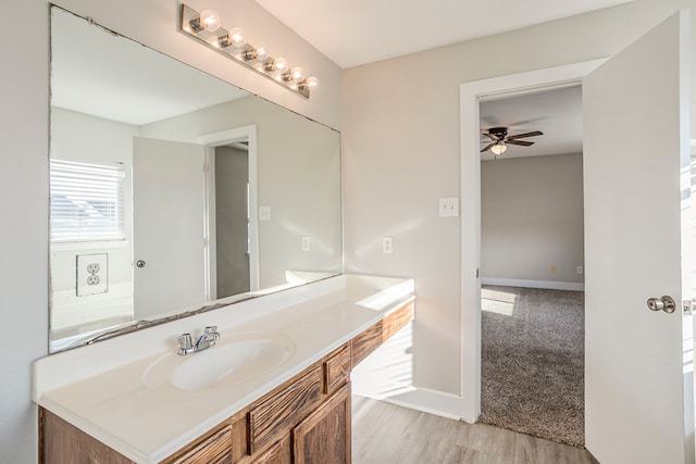 bathroom with a ceiling fan, baseboards, wood finished floors, and vanity