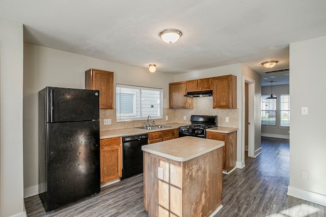 kitchen with decorative backsplash, under cabinet range hood, light countertops, black appliances, and a sink