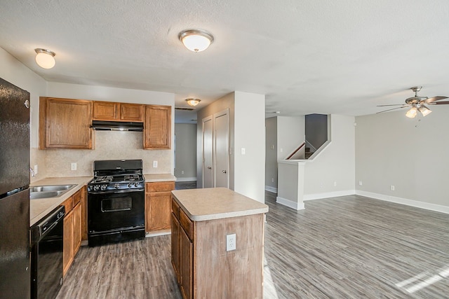 kitchen featuring black appliances, wood finished floors, and light countertops