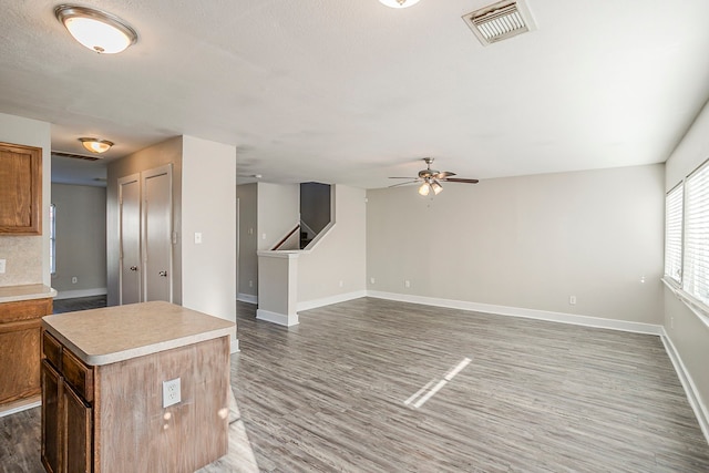 kitchen featuring light countertops, visible vents, a kitchen island, and wood finished floors