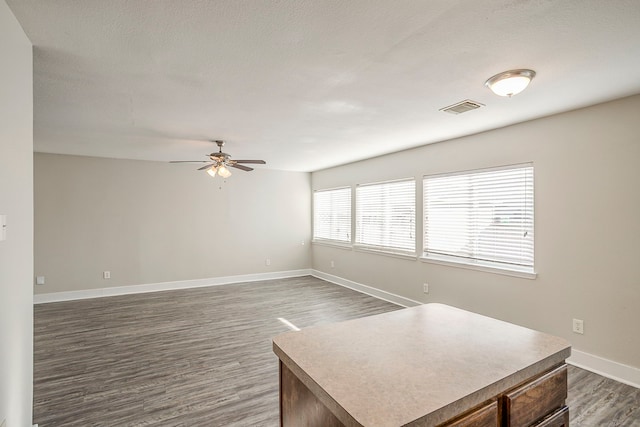 interior space featuring ceiling fan, dark wood-type flooring, visible vents, and baseboards