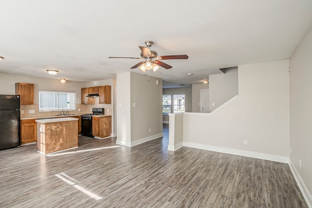 kitchen with dark wood-style flooring, a sink, open floor plan, brown cabinets, and black appliances