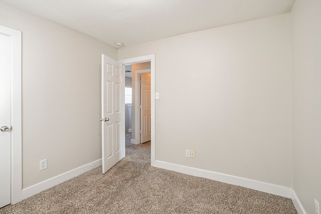 empty room with baseboards and light colored carpet