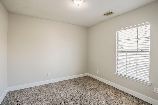 carpeted spare room with visible vents and baseboards