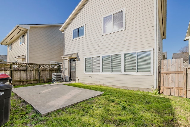 rear view of house featuring a patio, a yard, central AC unit, and fence