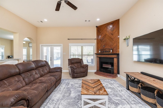 living room featuring baseboards, a fireplace, visible vents, and french doors