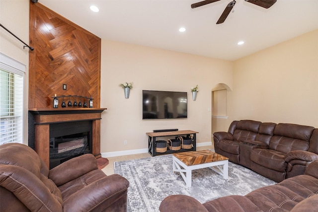 living room featuring arched walkways, ceiling fan, recessed lighting, baseboards, and a glass covered fireplace