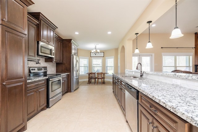 kitchen with appliances with stainless steel finishes, pendant lighting, a sink, and tasteful backsplash