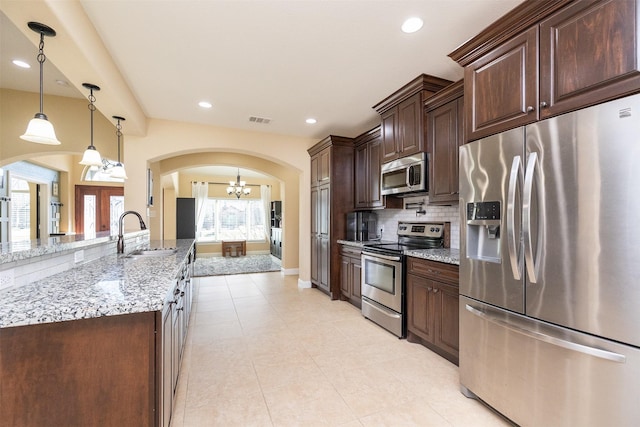 kitchen with arched walkways, stainless steel appliances, a sink, visible vents, and dark brown cabinets