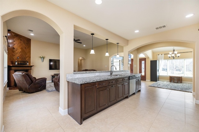 kitchen with dark brown cabinetry, visible vents, dishwasher, light stone counters, and a sink