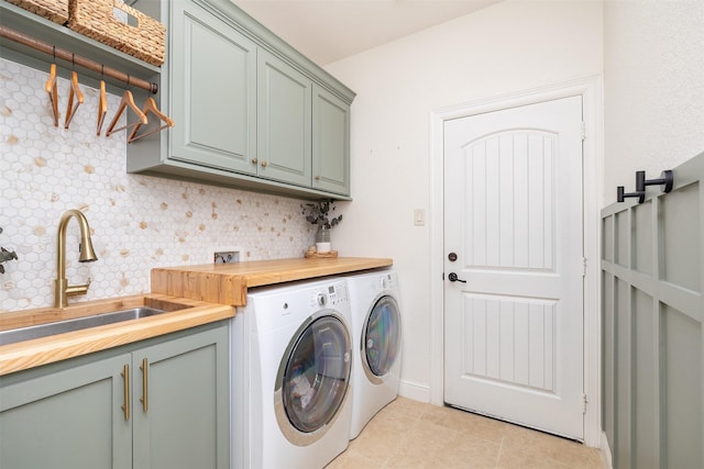 laundry room featuring cabinet space, washing machine and dryer, light tile patterned floors, and a sink