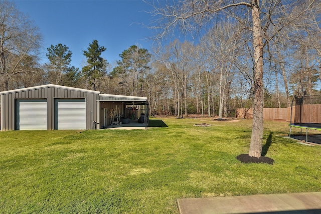 view of yard with an outbuilding, a garage, fence, a pole building, and a trampoline