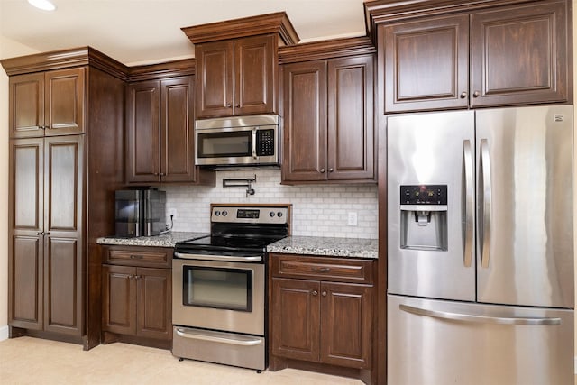 kitchen featuring stainless steel appliances, light stone counters, backsplash, and dark brown cabinets