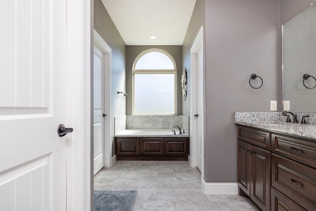 bathroom with a garden tub, vanity, and baseboards