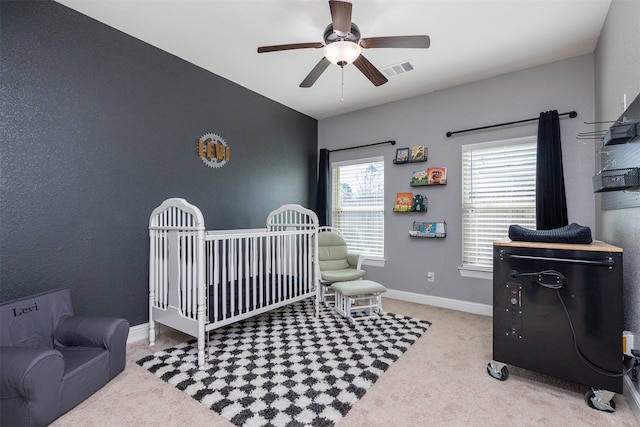 bedroom with baseboards, visible vents, ceiling fan, carpet, and a nursery area