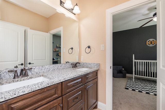 full bath with double vanity, baseboards, a ceiling fan, and a sink