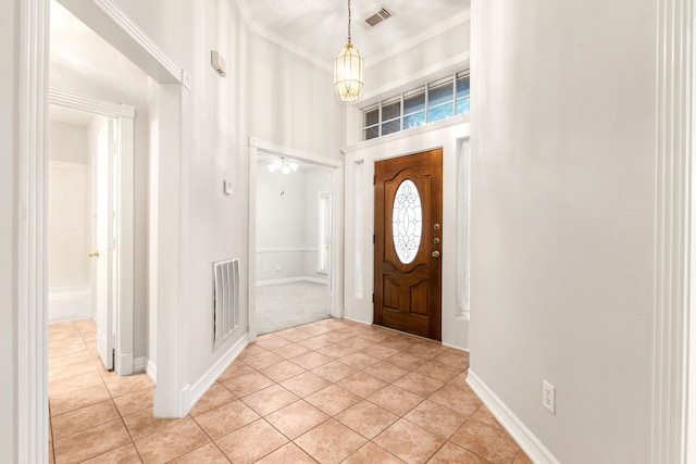 entrance foyer with a chandelier, visible vents, crown molding, and light tile patterned flooring