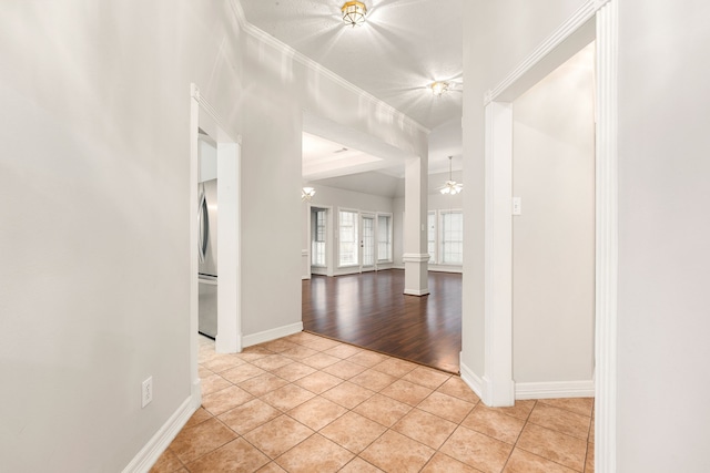 spare room featuring light tile patterned floors, ornamental molding, decorative columns, and baseboards