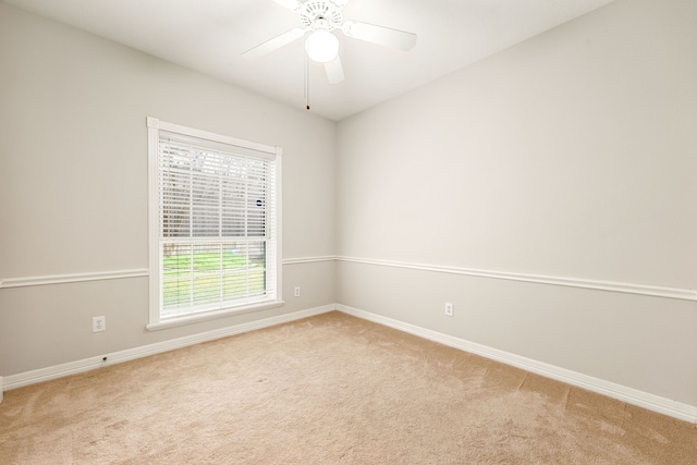 carpeted spare room featuring ceiling fan and baseboards