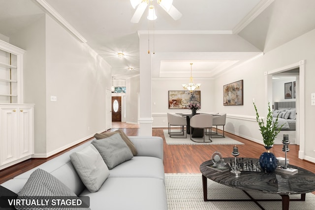 living room with a notable chandelier, baseboards, ornamental molding, and wood finished floors