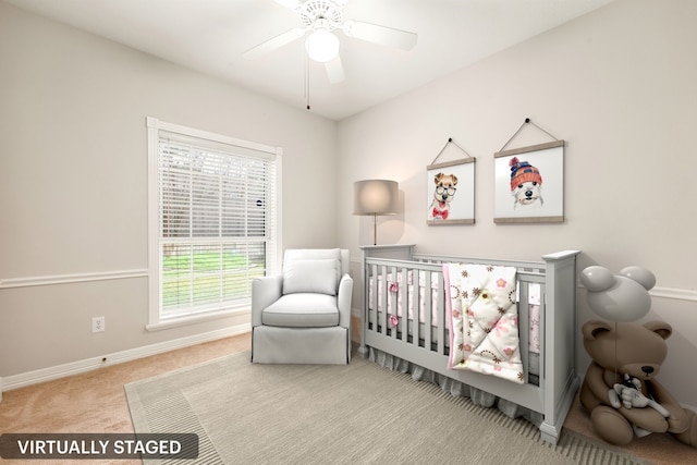 carpeted bedroom with a nursery area, baseboards, and a ceiling fan