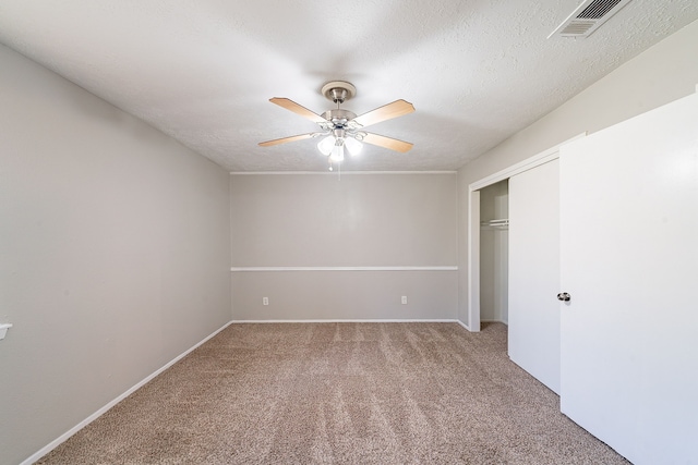 unfurnished bedroom with a textured ceiling, a closet, carpet flooring, and visible vents