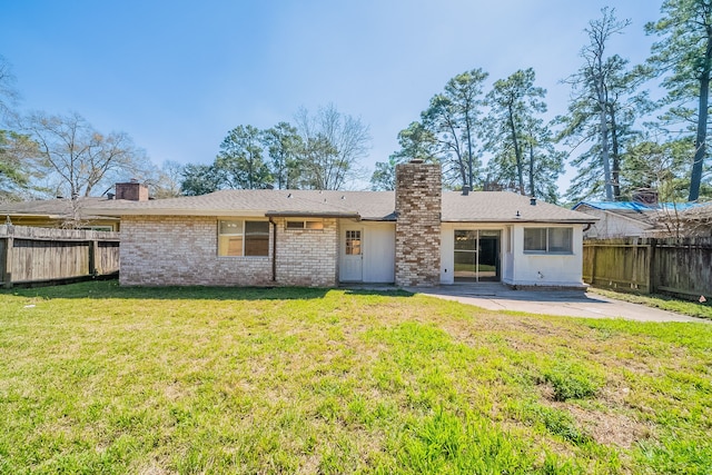 rear view of property featuring a fenced backyard, a lawn, a chimney, and a patio