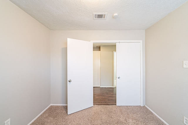 unfurnished bedroom with baseboards, carpet, visible vents, and a textured ceiling