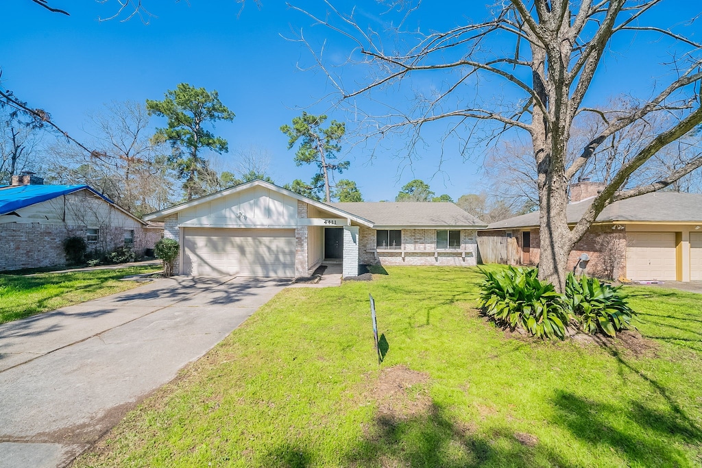 view of front of property with an attached garage, driveway, brick siding, and a front yard