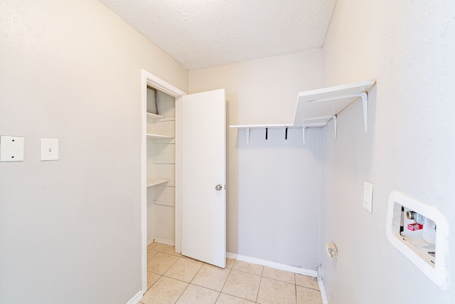 clothes washing area featuring laundry area, light tile patterned floors, baseboards, hookup for a washing machine, and a textured ceiling