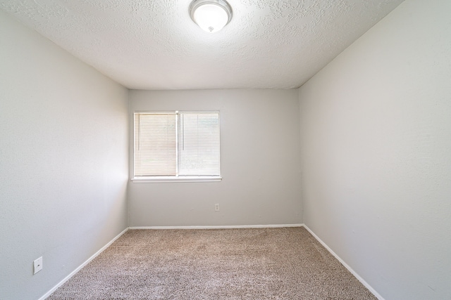 empty room with a textured ceiling, carpet flooring, and baseboards