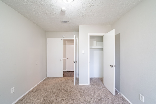 unfurnished bedroom featuring baseboards, visible vents, a textured ceiling, carpet flooring, and a closet