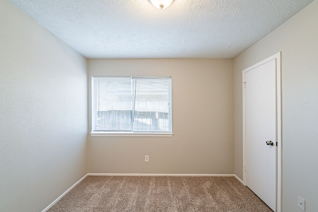 carpeted empty room with a textured ceiling and baseboards