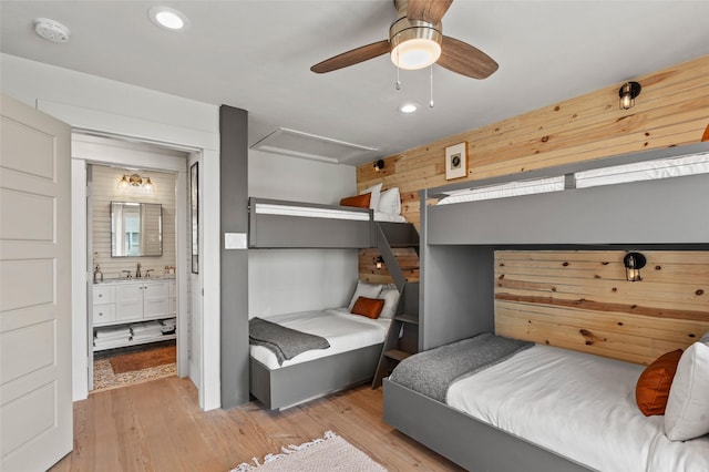 bedroom featuring wooden walls, recessed lighting, a sink, light wood-type flooring, and attic access