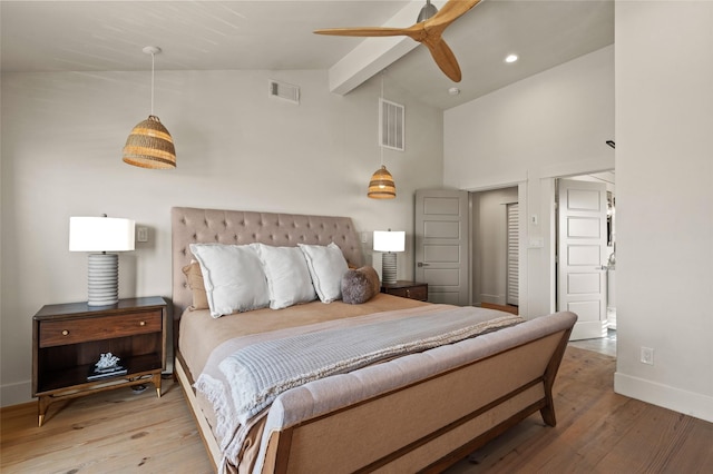 bedroom featuring beam ceiling, visible vents, baseboards, and wood finished floors