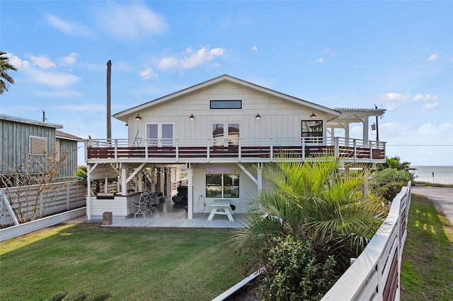 rear view of house featuring a lawn, a wooden deck, and fence