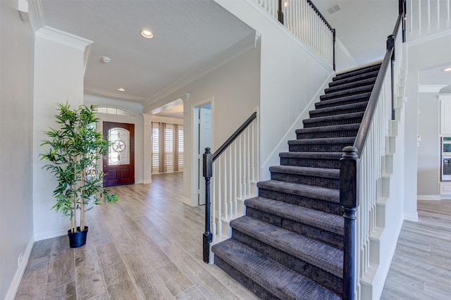 foyer entrance with light wood-style floors, visible vents, crown molding, and baseboards