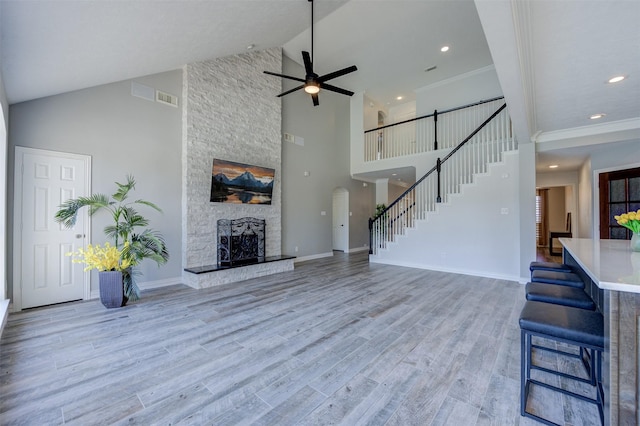 living room with light wood-style flooring, a fireplace, visible vents, baseboards, and stairway