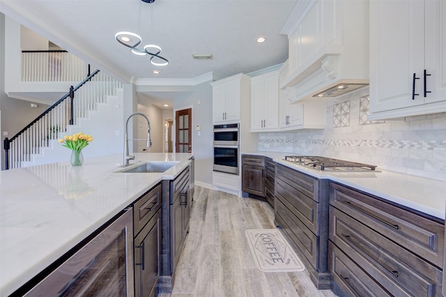 kitchen with wine cooler, stainless steel appliances, visible vents, white cabinets, and a sink