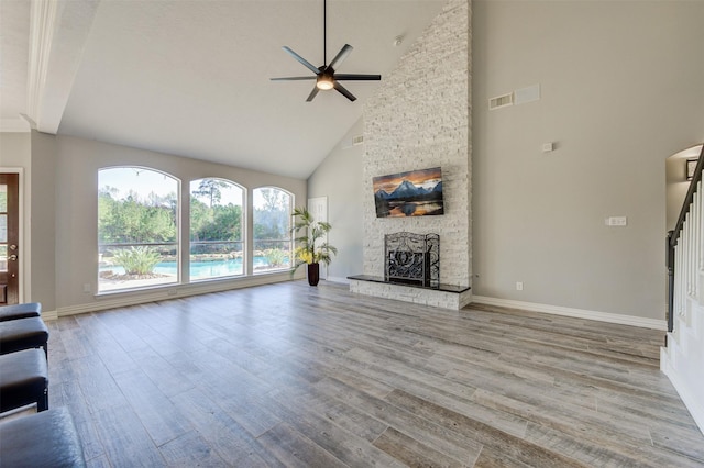 unfurnished living room with a fireplace, stairway, baseboards, and wood finished floors